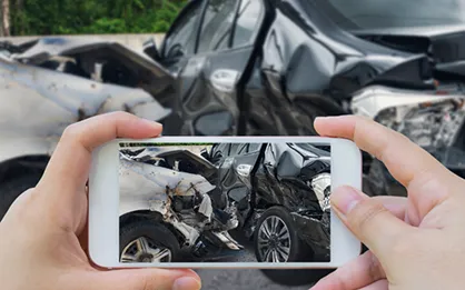 Persona sacando fotos del daño en un auto después de un choque